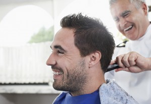 Closeup of happy man getting an haircut from barber in hair salo